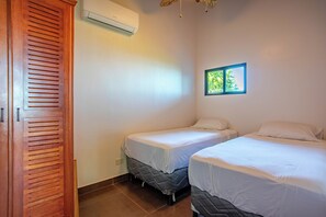 Una habitación con dos camas, un armario de madera y aire acondicionado.