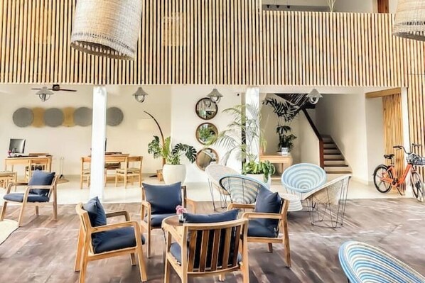 A spacious indoor area with wooden furniture, a staircase, and various plants.
