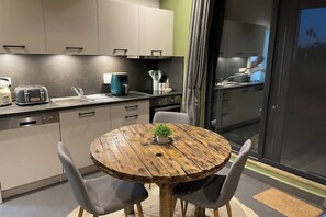 Eine moderne Küche mit einem runden Holztisch, grauen Stühlen, einer Kaffeemaschine und einem Toaster.