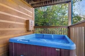 Una cabaña de madera con un jacuzzi en un balcón.