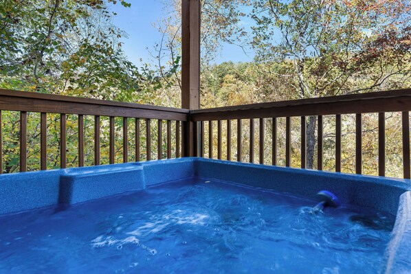Un jacuzzi con cubierta de madera y vista a los árboles.