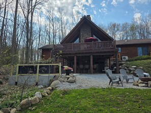 Une cabane dotée d’une cheminée en pierre, d’un espace salon extérieur et d’une terrasse couverte.