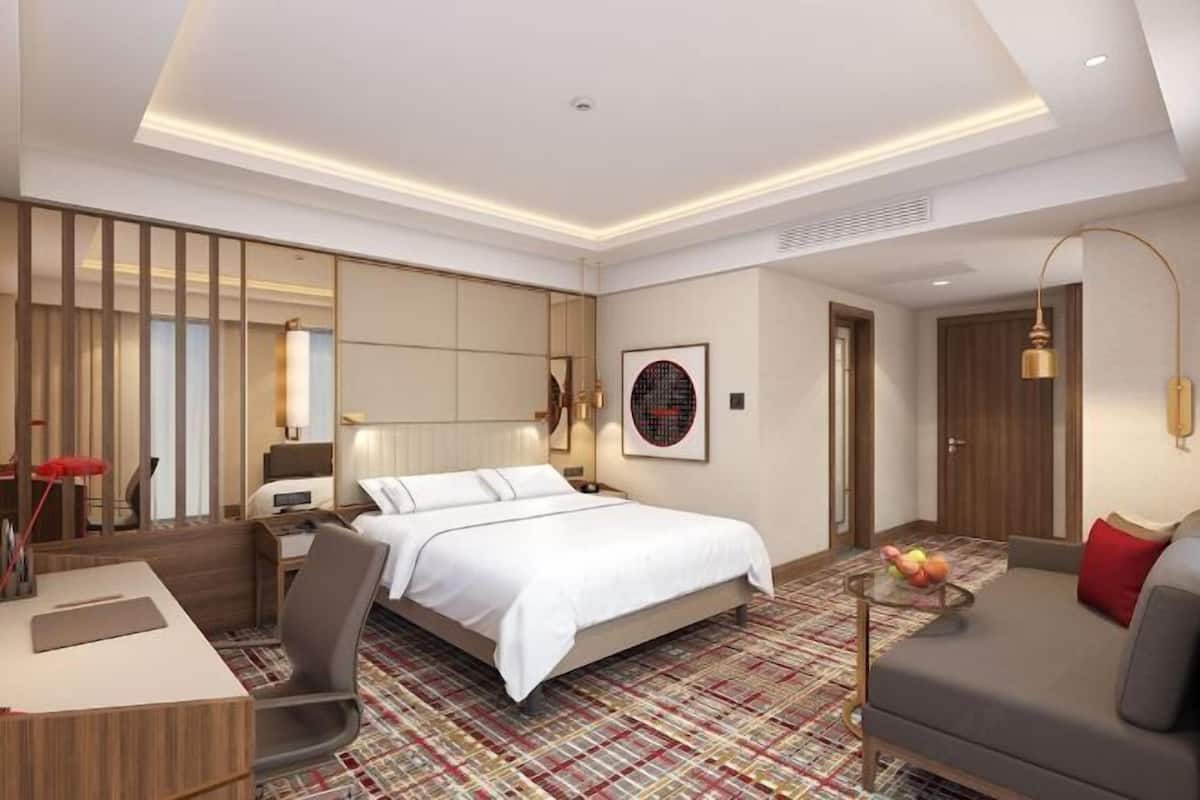 Une chambre d’hôtel avec un grand lit, un bureau, un canapé et une moquette à motifs.