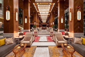 A hotel lobby with a central seating area, chandeliers, and a view down a long corridor. - Movenpick Hotel Istanbul Asia Airport (Istanbul)