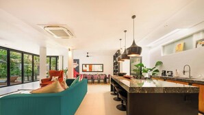 A modern kitchen with a central island, pendant lighting, and a dining area with a sofa and chairs.