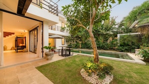 A modern two-story house with a patio, a swimming pool, and lush greenery.