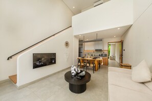 A modern living room with a staircase, a dining area, and a kitchen.