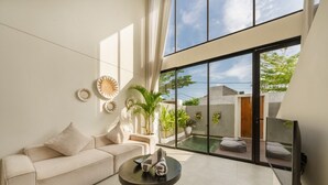 Ein modernes Wohnzimmer mit einer Couch, einem Couchtisch und großen Fenstern.