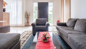 A modern living room with a sofa, armchair, and a coffee table with a red runner. - Rehat at Villa Golf Island Dago Resort I (Cimenyan)
