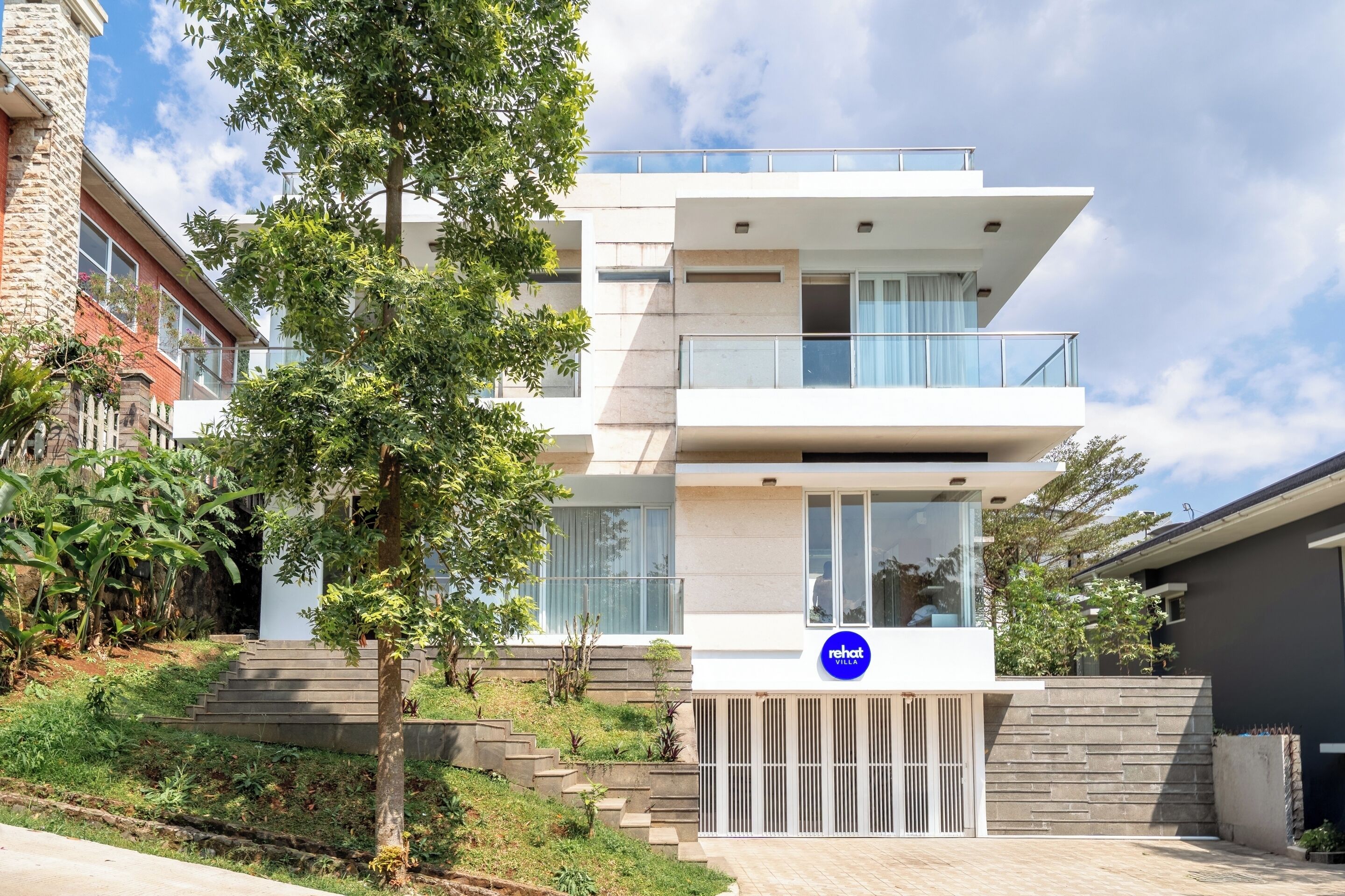 Eine moderne Villa mit Flachdach, Balkon und geschlossenem Eingangstor.