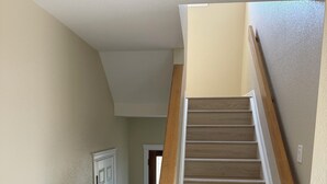 Una escalera de madera con barandilla que lleva a un rellano con una puerta.