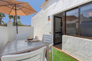 Un patio con tavolo, sedie, ombrellone e una porta d'ingresso.