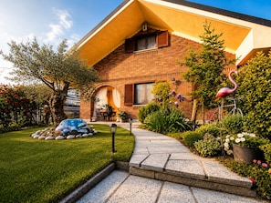 A brick house with a garden, a flamingo statue, and a bicycle.