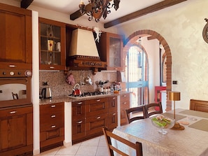 A kitchen with wooden cabinets, a stove, and a dining area with a table and chairs.