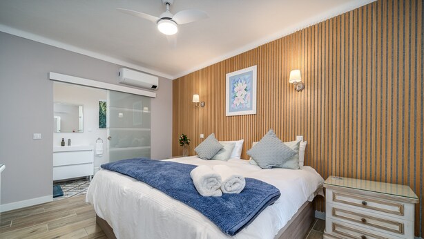 A bedroom with a bed, bedside tables, a ceiling fan, a wall-mounted air conditioner, and a large window. - Room 'Orange Blossom Grove -  2' with Shared Terrace, Wi-Fi and Air Conditioning (São Bartolomeu de Messines)