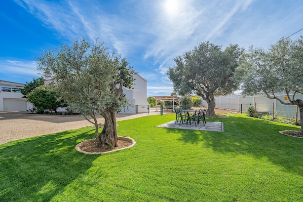 Un espace extérieur bien entretenu, doté d’une terrasse, de sièges et d’arbres.