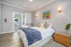 Un dormitorio con cama, mesita de noche y un cuadro en la pared.