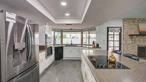 A modern kitchen with stainless steel appliances, granite countertops, and a large island with a gas stove.