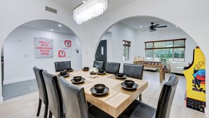 A dining area with a large table, chairs, and a chandelier.