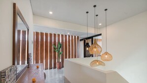 Un espace d’accueil moderne avec un comptoir en bois, une plante en pot et un grand miroir.