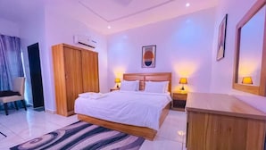 Una habitación de hotel con cama, lámparas de noche, escritorio, armario y espejo.