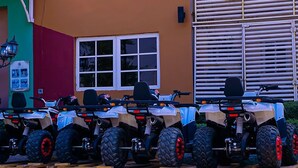 Una fila de cuatrimotos estacionadas frente a un edificio con ventana y puerta.