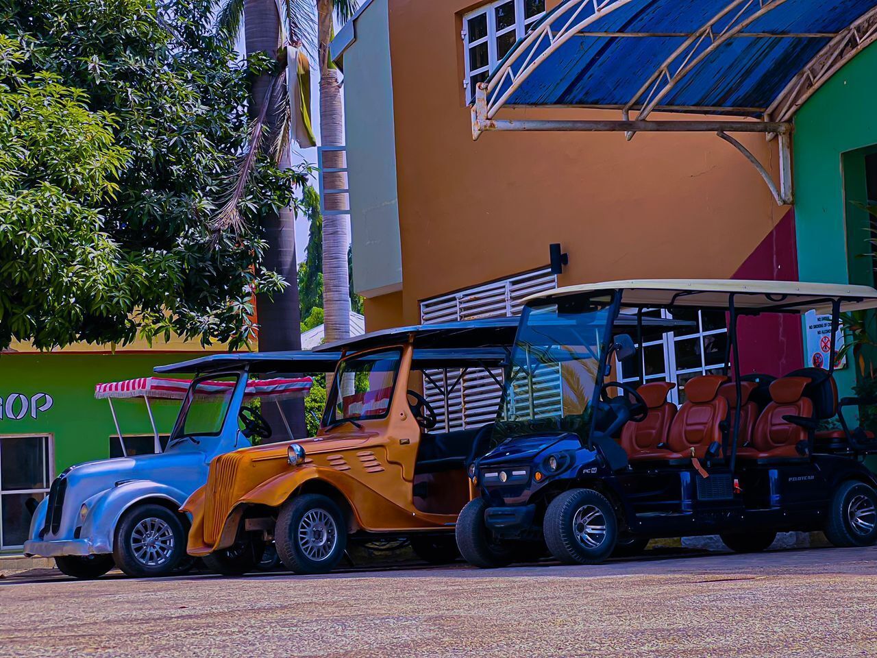 A colorful building with a sign that reads "SHOP" and a parked vehicle with a roof.