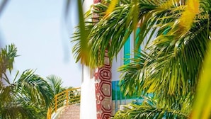 Un edificio con una escalera en espiral, palmeras y un pilar decorado.
