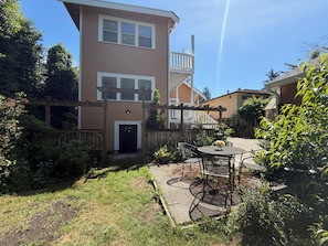 Una casa de dos pisos con un patio, una valla de madera y un pequeño jardín.