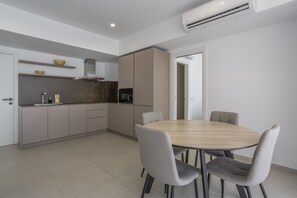Une cuisine moderne avec une table à manger ronde et des chaises, des placards intégrés et un appareil de climatisation.