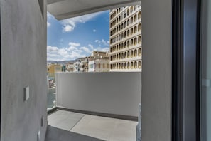 A balcony with a view of a cityscape, including a building with multiple balconies.