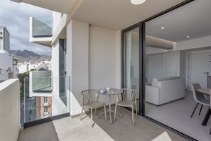 A modern apartment with a balcony, a dining area, and a living room with a sofa.
