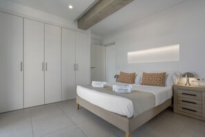 Une chambre à coucher comprenant un lit, des tables de chevet, une armoire et un luminaire fixé au mur.