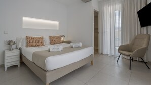 Ein modernes Hotelzimmer mit Bett, Nachttischen, einem Flachbildfernseher und einem Sessel.