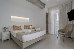 A modern hotel room with a bed, bedside tables, a flat-screen TV, and a chair.