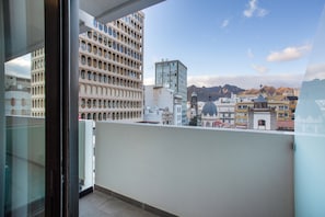 A balcony with a cityscape view, including a building with a unique facade and a modern glass structure.