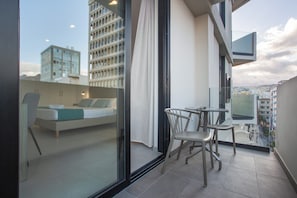 A modern apartment with a balcony, a bed, a table, and chairs.