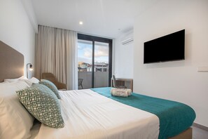 Une chambre d’hôtel avec un lit, une télévision, un bureau et une vue sur la ville.