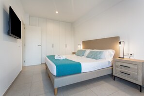 Una camera da letto moderna con un letto, comodini, una TV e un armadio.