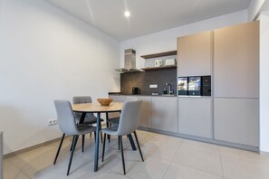 Una cucina moderna con tavolo, sedie e forno integrato.