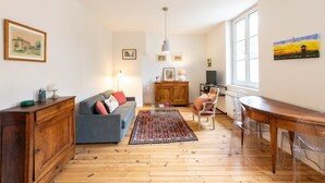A spacious living room with a sofa, a wooden cabinet, a dining table, and a kitchen area. - Bright and quiet apartment in the heart of Lyon (Lyon)