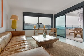 Een moderne woonkamer met een leren bank, een houten bijzettafeltje en uitzicht door grote glazen deuren.