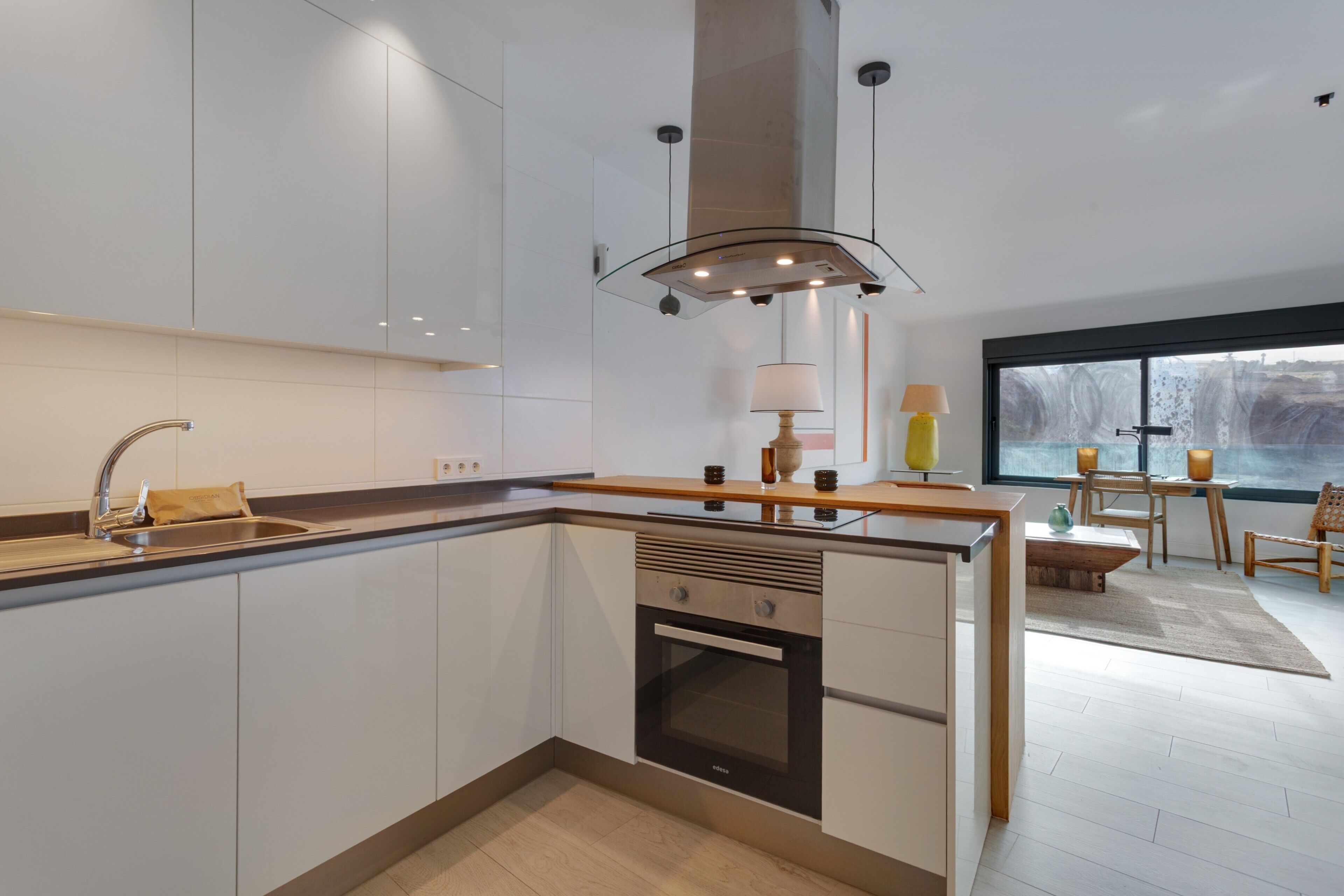 A modern kitchen with a large island, built-in oven, and a window with a view.