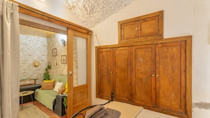 Une pièce comprenant une armoire en bois, un canapé, une petite table et un miroir.