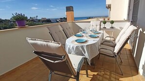 A round table with chairs on a balcony, overlooking a coastal view. - Relaxation, Golf and Beach (Velez-Malaga)