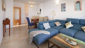 A living room with a blue sofa, a coffee table, and a dining area with chairs and a table. - Relaxation, Golf and Beach (Velez-Malaga)