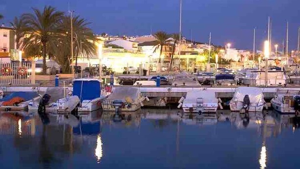 A marina with boats docked, palm trees, and buildings in the background. - Relaxation, Golf and Beach (Velez-Malaga)