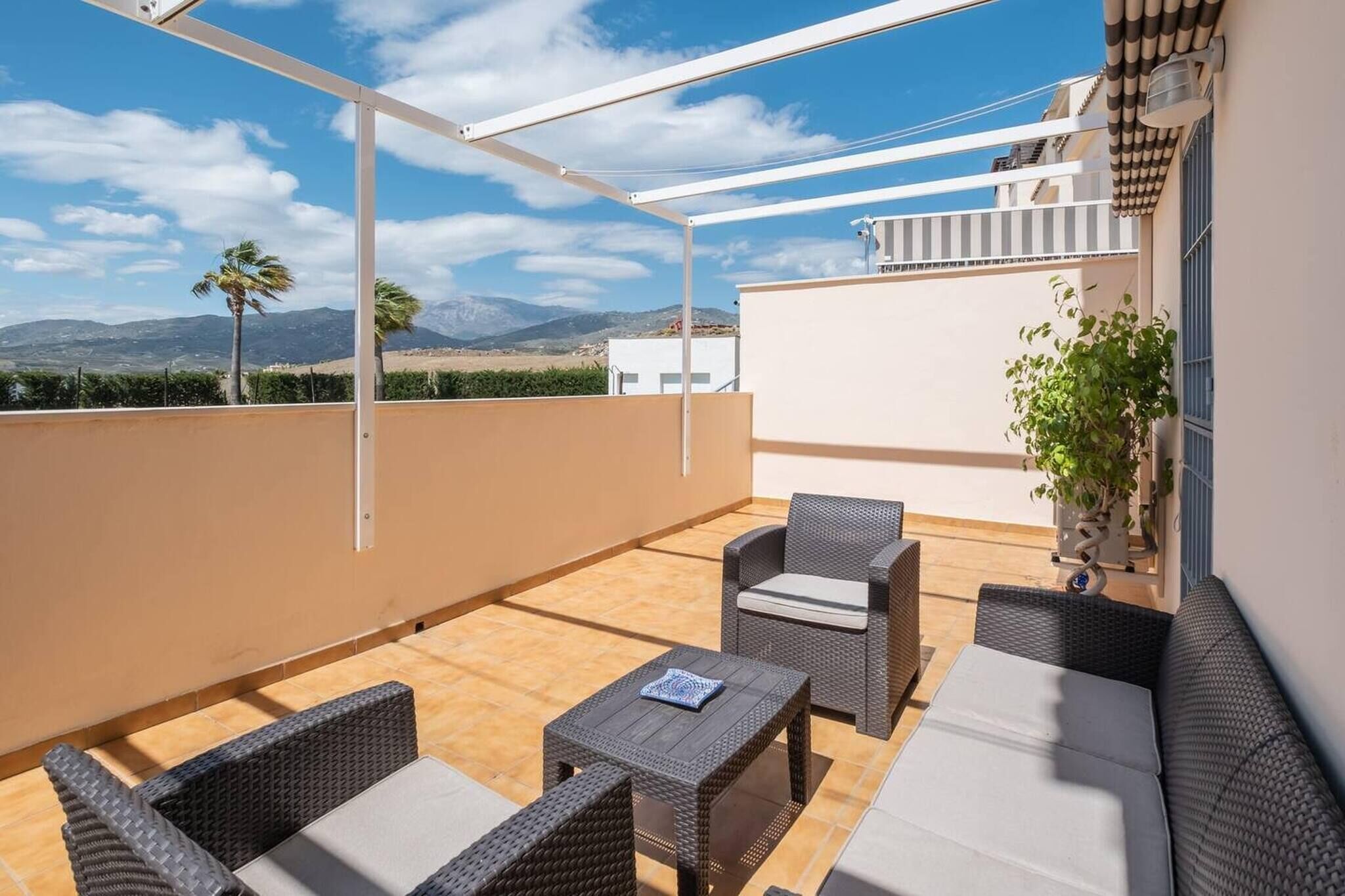 Une terrasse sur le toit, aménagée avec des meubles en osier, une petite table et une plante en pot.