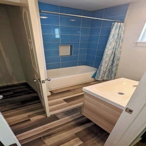 A bathroom with a bathtub, a shower curtain, and a sink. - 2 Large Bedrooms | Private | Downtown (Manchaca)