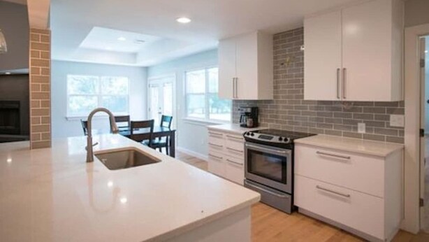 A modern kitchen with white cabinetry, a built-in oven, and a large island with a sink.